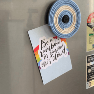 Handmade circular macramé evil eye fridge magnet in shades of blue, off white, and black, displayed on a refrigerator