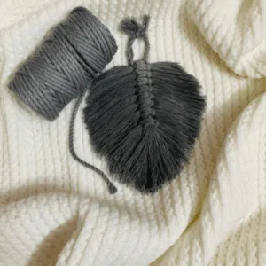 Handcrafted mini macramé leaf wall hanging in charcoal grey cotton, with soft textured fringe and central spine