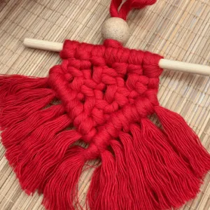 Handcrafted red mini macramé wall hanging with fringe, wooden bead, and hanging rod