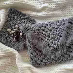 Handcrafted grey macramé bag with fringed flap, artisan knotting, and spacious cotton body